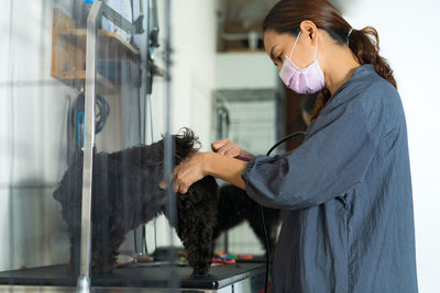 Woman grooming black dog at home