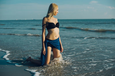 Woman standing in sea against sky