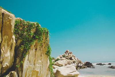 Rock formations in sea against clear blue sky