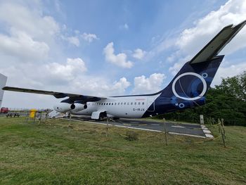 Airplane on airport runway against sky