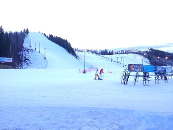 People on snow covered landscape against clear sky