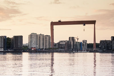 Buildings by river at eriksberg against sky during sunset