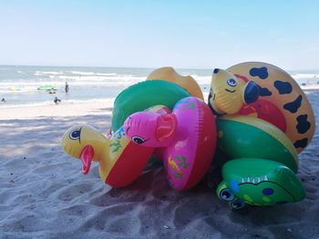 Close-up of toys on beach against sky