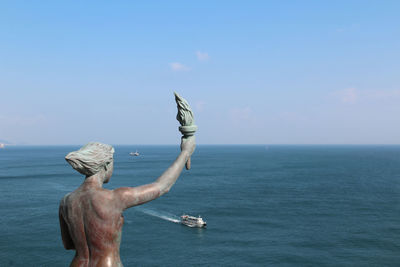 Rear view of shirtless man in sea against sky