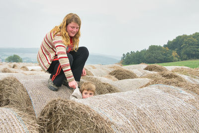 Woman with arms raised on farm against sky