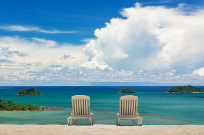 Deck chairs on beach against sky