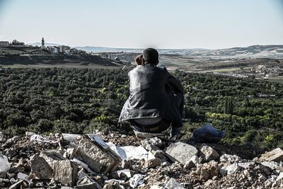 Rear view of man on rock against sky