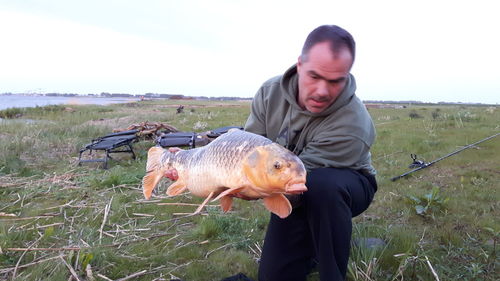 Man with dog standing on field against sky