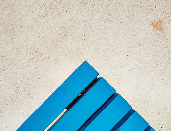 Minimalist overhead photo of a blue bench.