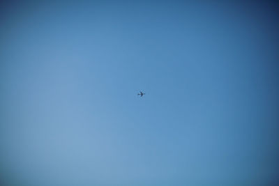 Low angle view of airplane against clear blue sky