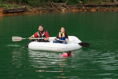 People on boat in lake while little girl swimming