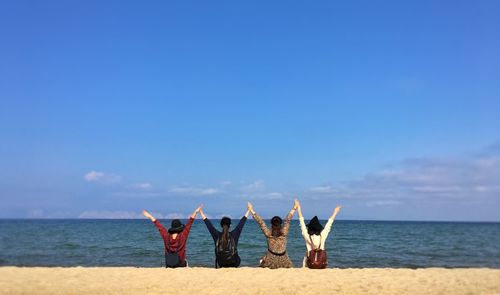 Low section of people at beach against blue sky