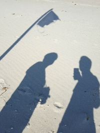 High angle view of people shadow on wet sand