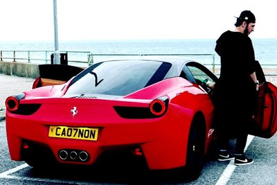 Man standing by car on sea