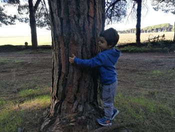 Full length of smiling girl standing on tree trunk