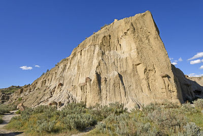 Low angle view of rocky mountain against blue sky