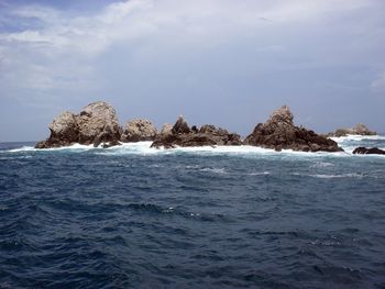 Scenic view of rocks in sea against sky