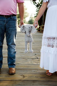 Low section of couple holding stuffed toy while standing outdoors