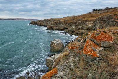 Rock formation on sea shore against sky