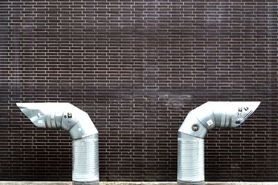 Close-up of exhaust pipes against brick wall