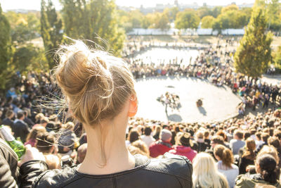 Rear view of woman looking at event while sitting with crowd