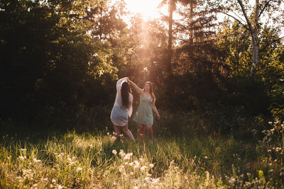 Happy lesbian couple dancing in forest during summer