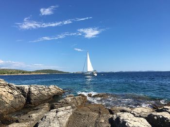 Sailboat sailing on sea against blue sky