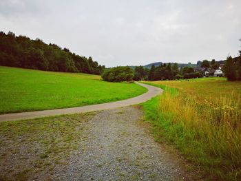 Scenic view of road amidst field against sky
