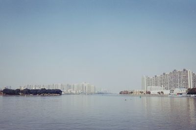 Scenic view of sea and buildings against clear sky