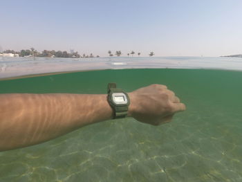 Midsection of man swimming in pool against sea