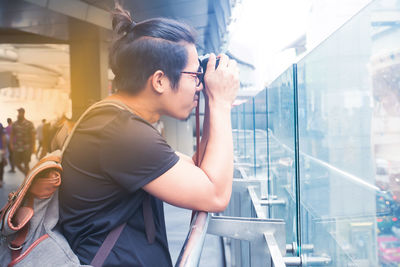 Side view of young woman looking through glass window