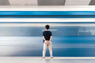 Rear view of man standing on escalator