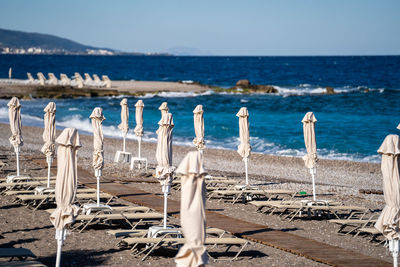 Empty beach chairs and closed sun umbrellas on the beach in greece.