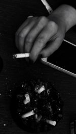 Midsection of person holding cigarette on table