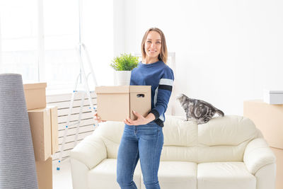 Portrait of woman holding cardboard box at home