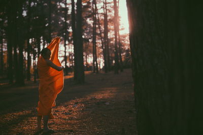 Monk in traditional clothing standing against trees