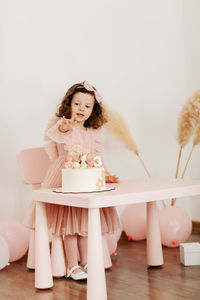 Happy little girl with a birthday cake at the table.