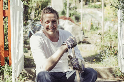 Portrait of happy man with gardening fork relaxing at yard