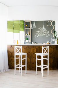 Cozy interior of the living room with a wooden bar counter and white chairs