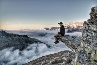 Rear view of man standing on mountain against sky during sunset