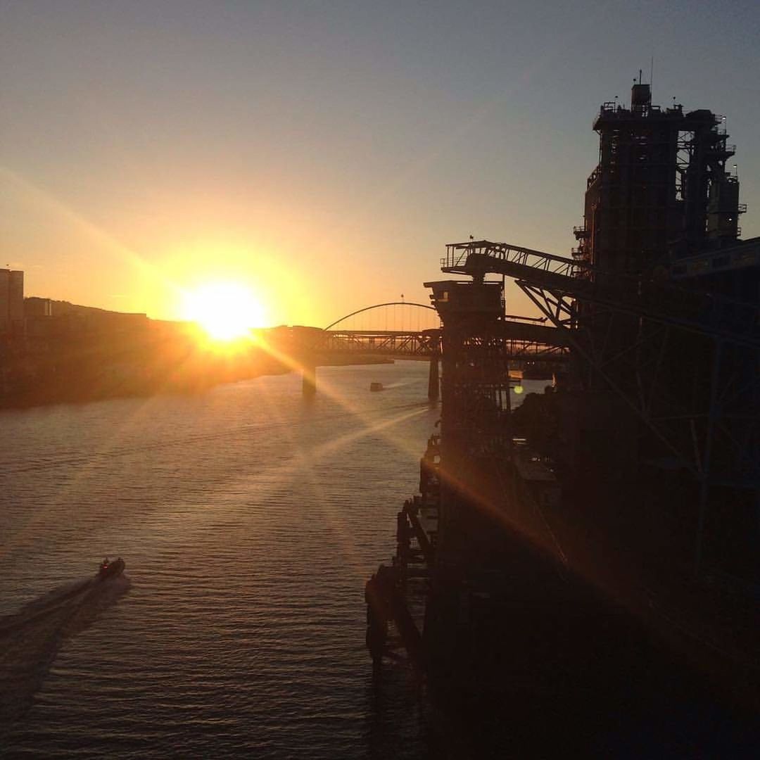 sky, sunset, built structure, water, architecture, sunlight, sun, nature, lens flare, no people, transportation, connection, building exterior, sunbeam, outdoors, bridge, orange color, sea, industry, bright