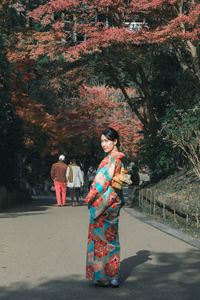 Portrait of young woman standing on road at park