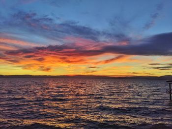 Scenic view of sea against dramatic sky during sunset