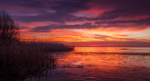 Scenic view of sea against dramatic sky during sunset