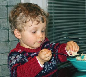 Baby boy having food while sitting by window at home