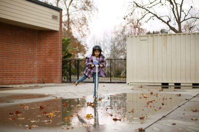 Girl riding push scooter on wet street