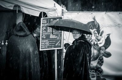 Portrait of woman with umbrella standing at market during rainy season