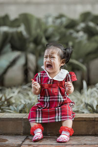 Full length of cute baby girl sitting on footpath