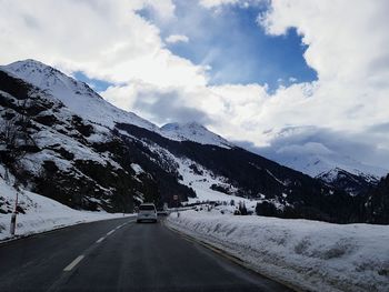 Road amidst snowcapped mountains against sky