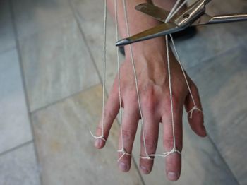 Cropped hand with strings over flooring